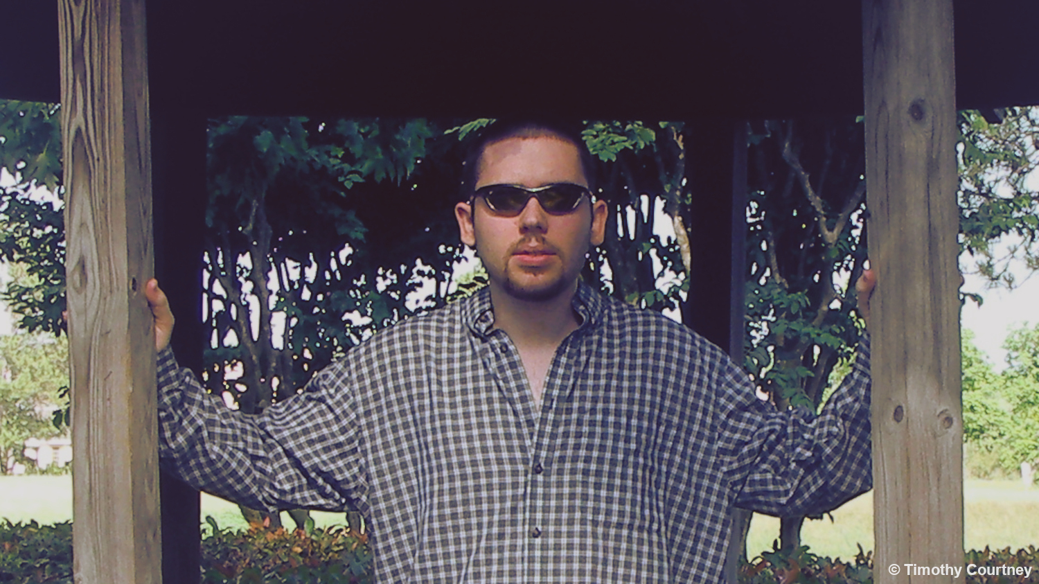 Timothy Courtney is standing in the entry of a wooden outdoor gazebo