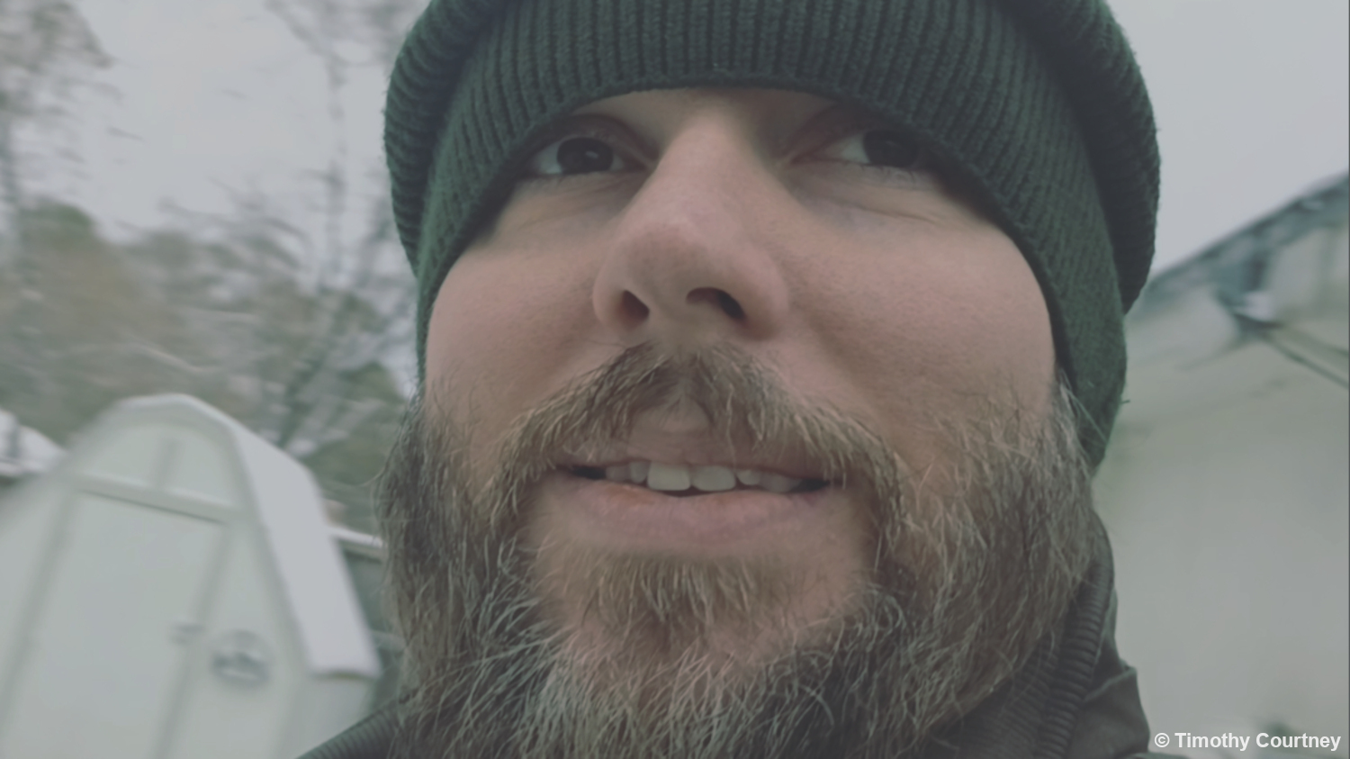 This is a close-up headshot with a green sweater cap on outside in the snow