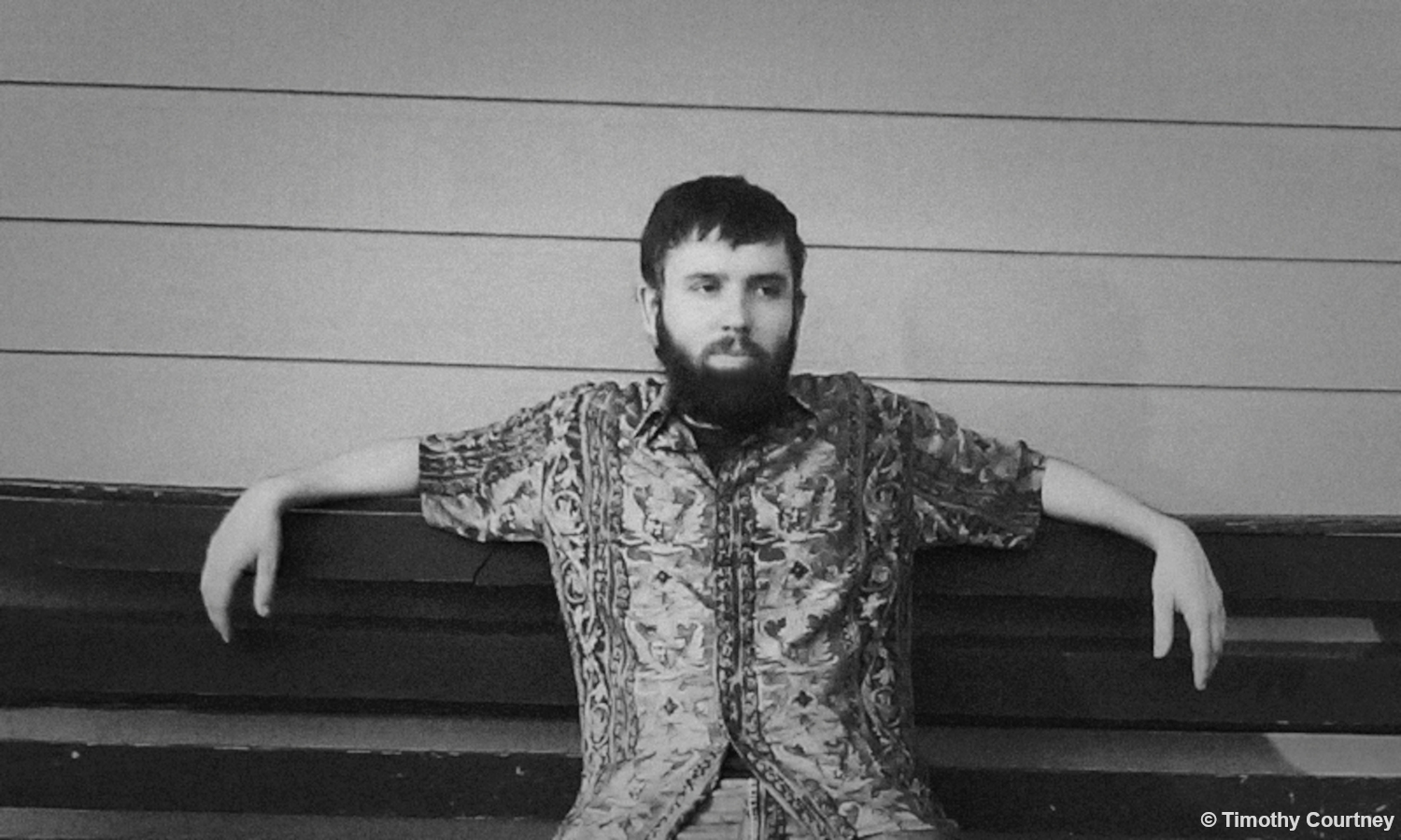 Timothy Courtney sits waiting on a wooden bench